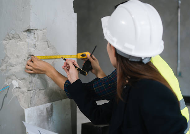 istock Asian male and female engineers wearing safety vests and helmets inspect structural elements, review blueprints, plan material choices bricks, steel, concrete during home renovation project on-site. 2222822313