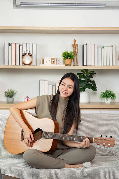 Joyful woman playing guitar at home. Relaxed and creative atmosphere.