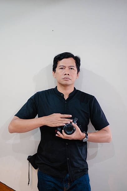 istock Professional Photographer Holding Camera Against Plain Wall Capturing Creative Imagery Concept 2222825133