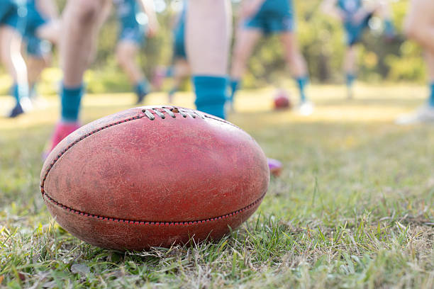 A football player scores a touchdown and falls to the grass