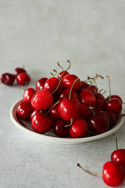 Image of juicy fresh red cherries with stalks in dish / seasonal summer fruit display emphasizing natural vibrancy