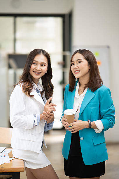 istock Two Asian businesswomen stand and talk about work. 2222831574