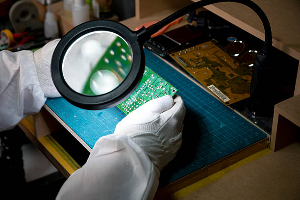 istock Horizontal profile shot of a female technician examining a printed circuit board through a magnifying glass at desk in a hi-tech electronics manufacturing plant., 2222834496