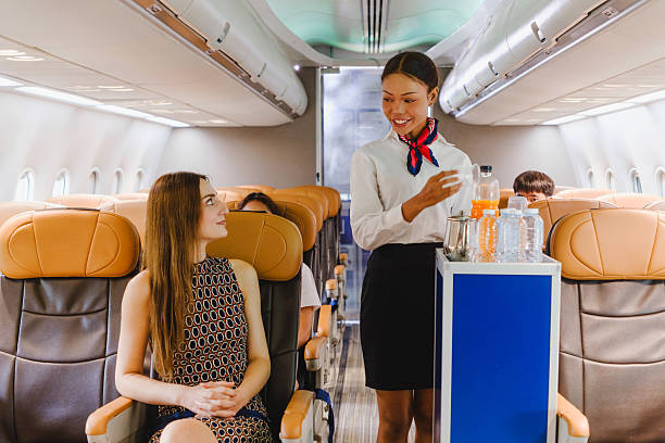 istock Flight attendant offering inflight refreshments to a seated passenger with a smile. Represents quality airline service, hospitality, and comfort during air travel in a modern cabin setting. 2222834975