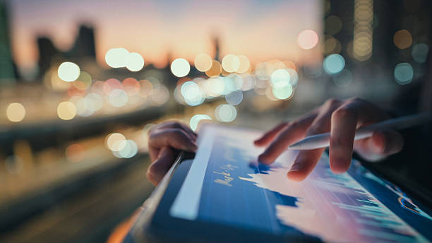 istock a person uses a tablet with financial data in a low-light urban setting, symbolizing night trading, business intelligence, and the rise of digital nomads in financial markets. 2222837957
