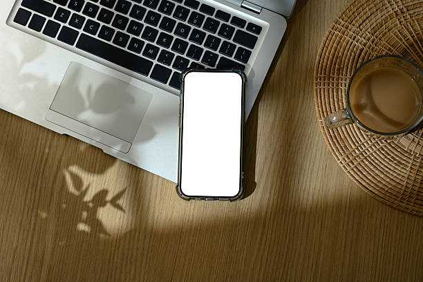 istock Smartphone with blank white screen placed on laptop keyboard next to coffee cup on wooden desk 2222840045