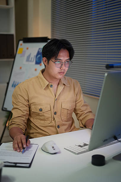 istock Focused businessman working late into the night, analyzing reports and entering data at computer 2222840188