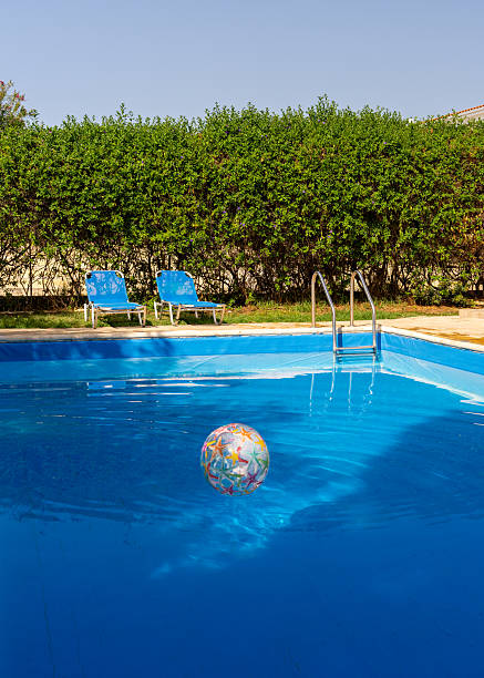 istock Bright inflatable beach ball drifting in swimming pool next to two empty lounge chairs. Playful and sunny vacation vibe, perfect for family, fun, and leisure content. 2222843017