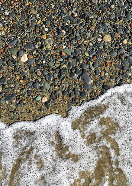 istock Close view of foamy wave reaching pebble beach. Natural seaside texture ideal for relaxation, wellness themes, and summer travel visuals. 2222843021