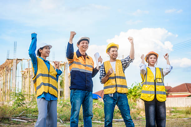 istock An elderly male engineer, a middle-aged man, and two young Asian women unite hands on  construction site, symbolizing teamwork, safety, professionalism,solidarity amid ongoing structural development 2222843391