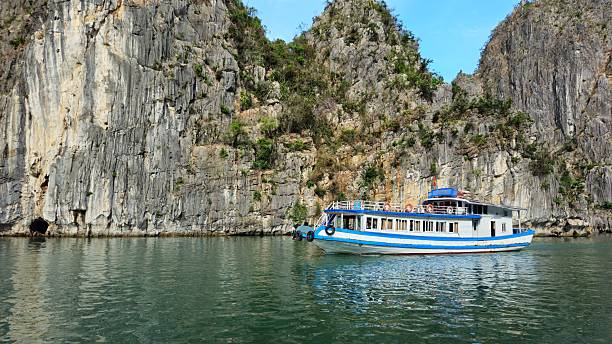 istock A tourist boat gliding past towering limestone cliffs reflected in the calm emerald waters in Ha Long bay, Vietnam. 2222847469