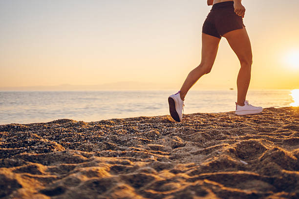 Woman bare foot walking on the summer beach. close up leg of young woman walking along wave of sea water and sand on the beach. Travel Concept.
