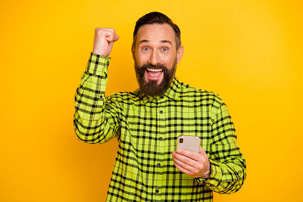 istock Portrait of attractive cheerful man using device celebrating good feedback isolated over bright yellow color background 2222850471