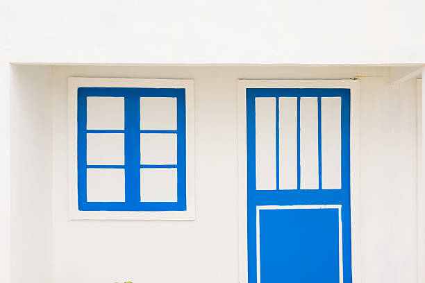 Minimalist white wall with vibrant blue door and window, clean architecture and simple design