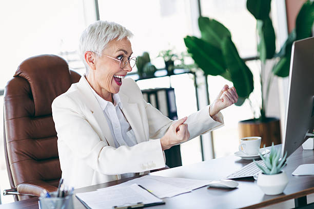 istock Happy senior businesswoman celebrating success at her office workspace while working on a project 2222854007
