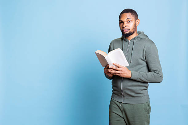 istock Confident happy person reading a book against blue background 2222854360