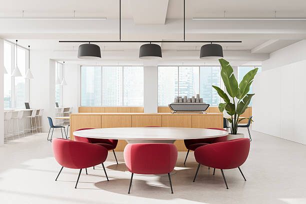 istock Modern office lounge interior with red chairs, round white table, large plant, and espresso machine in bright setting with city view windows. 3D Rendering 2222855325