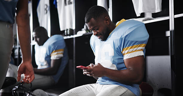 istock Football, player and texting with phone in locker room for message response, check notifications and game break. Sports, man and relax with smartphone for social media, online news and web connection 2222857804