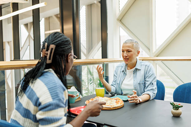 Pizza and Coffee Chat Between Coworkers in Trendy restaurant stock photo