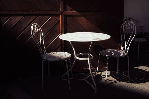 istock Vintage Wrought Iron Bistro Table and Chairs in Dramatic Shadow 2222859568