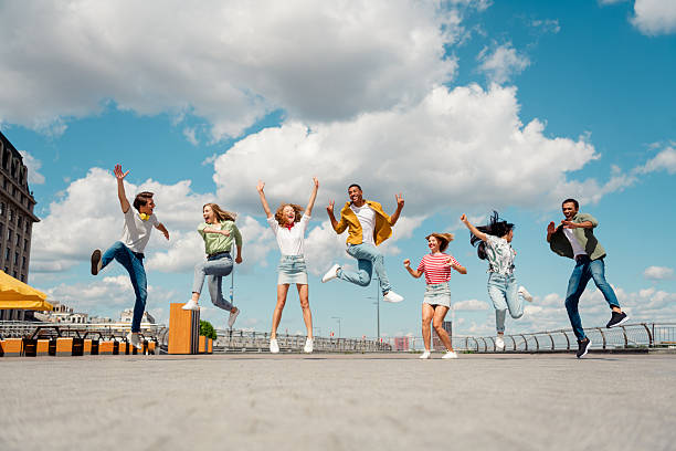 istock Students jumping outdoors during summer under a blue sky, enjoying a vibrant urban day in friendship. 2222859818