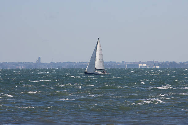 Sailboat sails the blue sea at grey weather. Mid shot