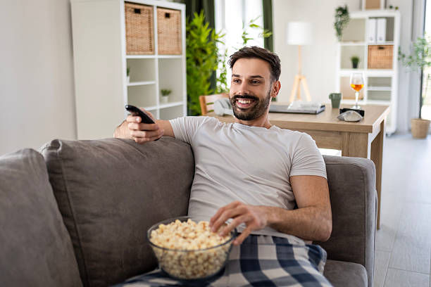 istock Man in Pajamas Relaxing with Popcorn and Remote 2222865130