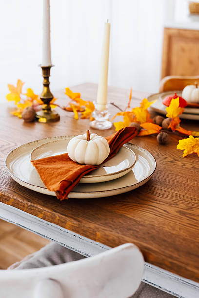 istock Decorative autumn table setting with white pumpkin and colorful leaves in cozy dining area 2222867456