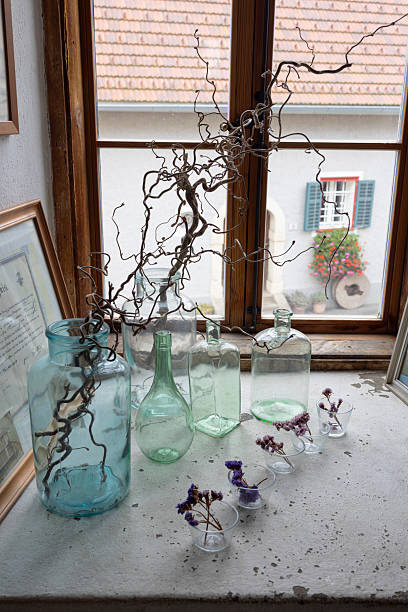 Curly branches and dried flowers decorating window sill with glass jars in Heimschuh, Styria, Austria, Europe