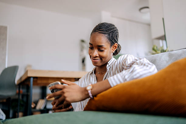 istock Smiling young woman using smart phone while sitting on a floor at home 2222869402