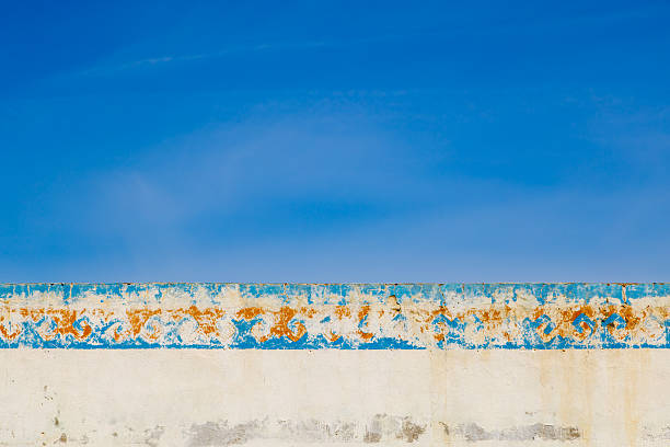 Weathered outdoor wall displays significant wear and peeling paint. Serene and calm atmosphere creates a minimalist backdrop, perfect for artistic expressions.