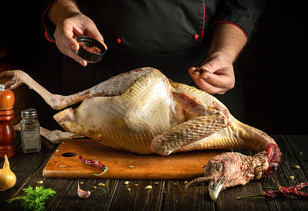 istock A chef expertly seasons a whole turkey on a wooden surface, with spices, herbs and tools placed around it. Warm lighting adds depth to the culinary setting 2222870585