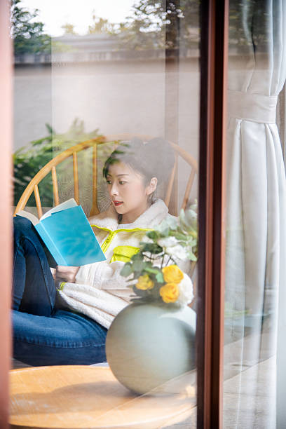 istock Women reading a book behind window 2222870711