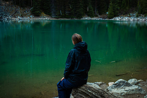 istock Woman sitting by emerald lake 2222870888
