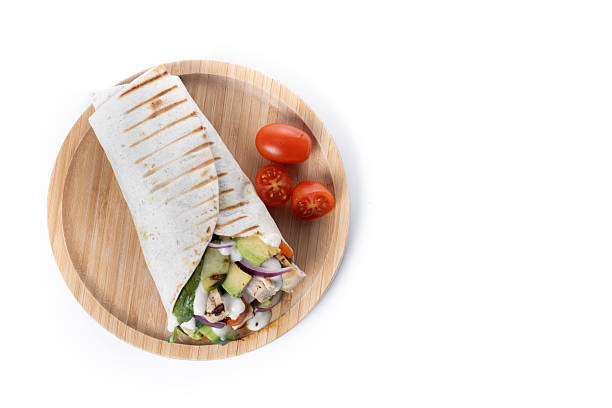 A delicious grilled chicken wrap with vegetables and avocado isolated on white background