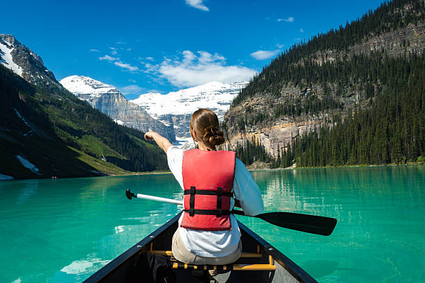 istock Woman in canoe pointing toward snowy mountain 2222873643