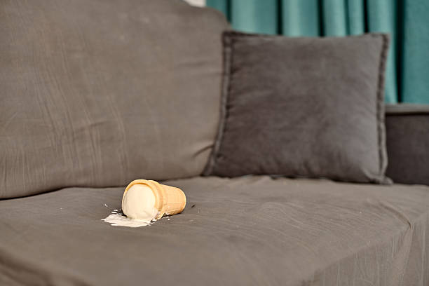 istock Fallen ice cream cone on gray sofa in living room setting 2222874617