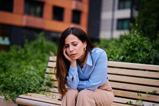 Young Woman Sitting on a Bench Looking Concerned in Urban Setting