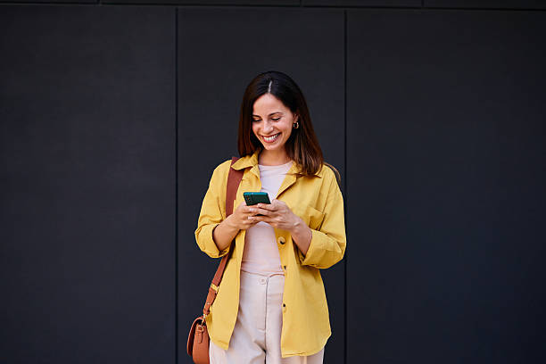 istock Smiling Woman Using Smartphone Walking Against Dark Urban Background 2222874899