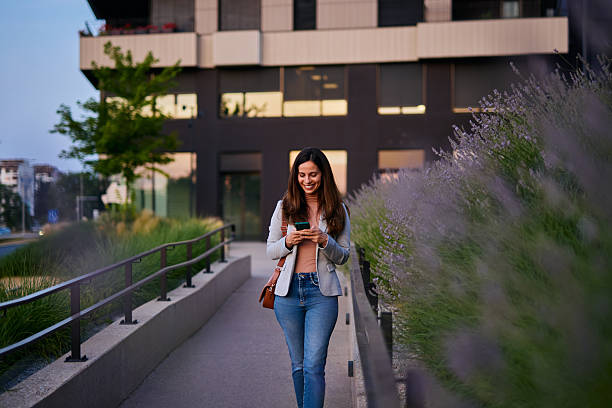 istock Smiling Woman Walking Outdoors While Typing on Her Phone 2222874926