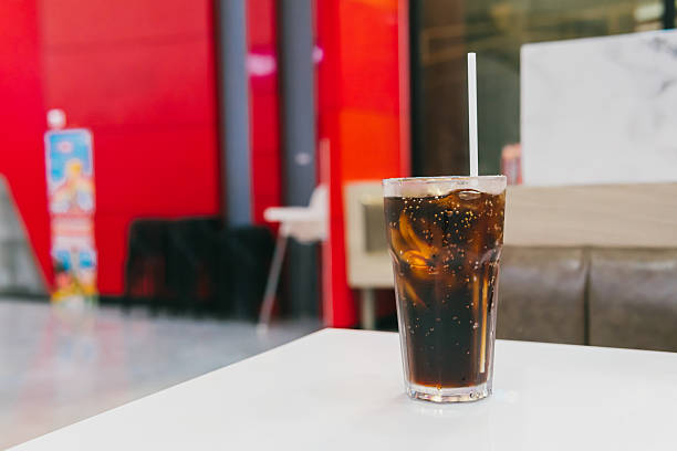 Refreshing Glass of Carbonated Soft Drink on a White Table in a Vibrant Modern Cafe Environment.