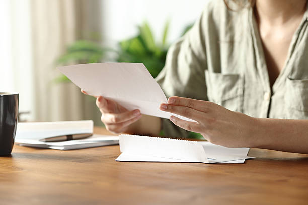 Woman hands at home reading paper letter stock photo