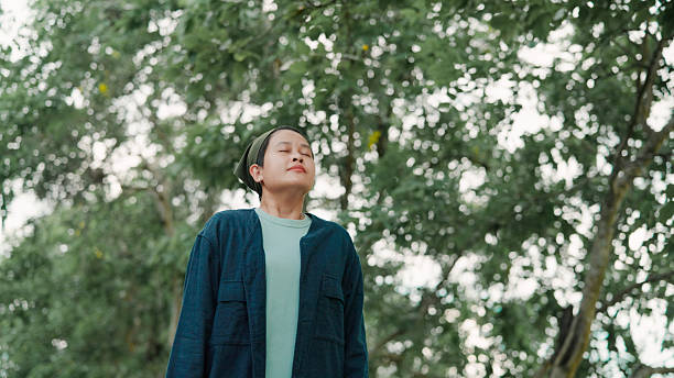istock Asian woman taking a deep breath in public park 2222878449