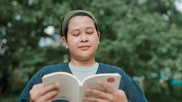 istock Asian woman reading book in public park 2222878687