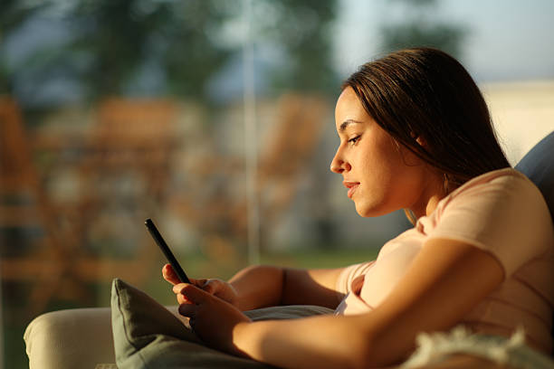 istock Relaxed woman using mobile phone at sunset at home 2222879175