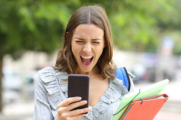 istock Excited student celebrating good news checking mobile phone 2222879303