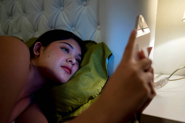 istock Indonesian southeast asian woman lying down on a bed and using a cellphone at night before sleep at home 2222879580