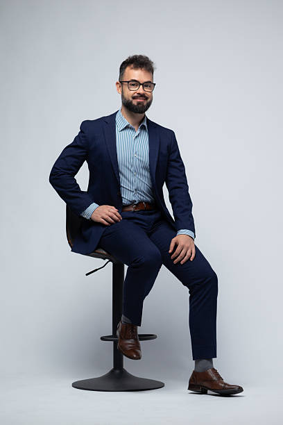 istock Serious Spanish Man in Blue Suit Sitting on Stool with Confident Look 2222882308