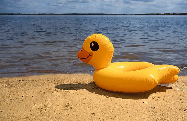 istock Bright yellow inflatable duck float on sandy beach by the water 2222885423