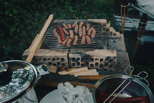 merguez sausages cooking on a barbecue grill with smoke